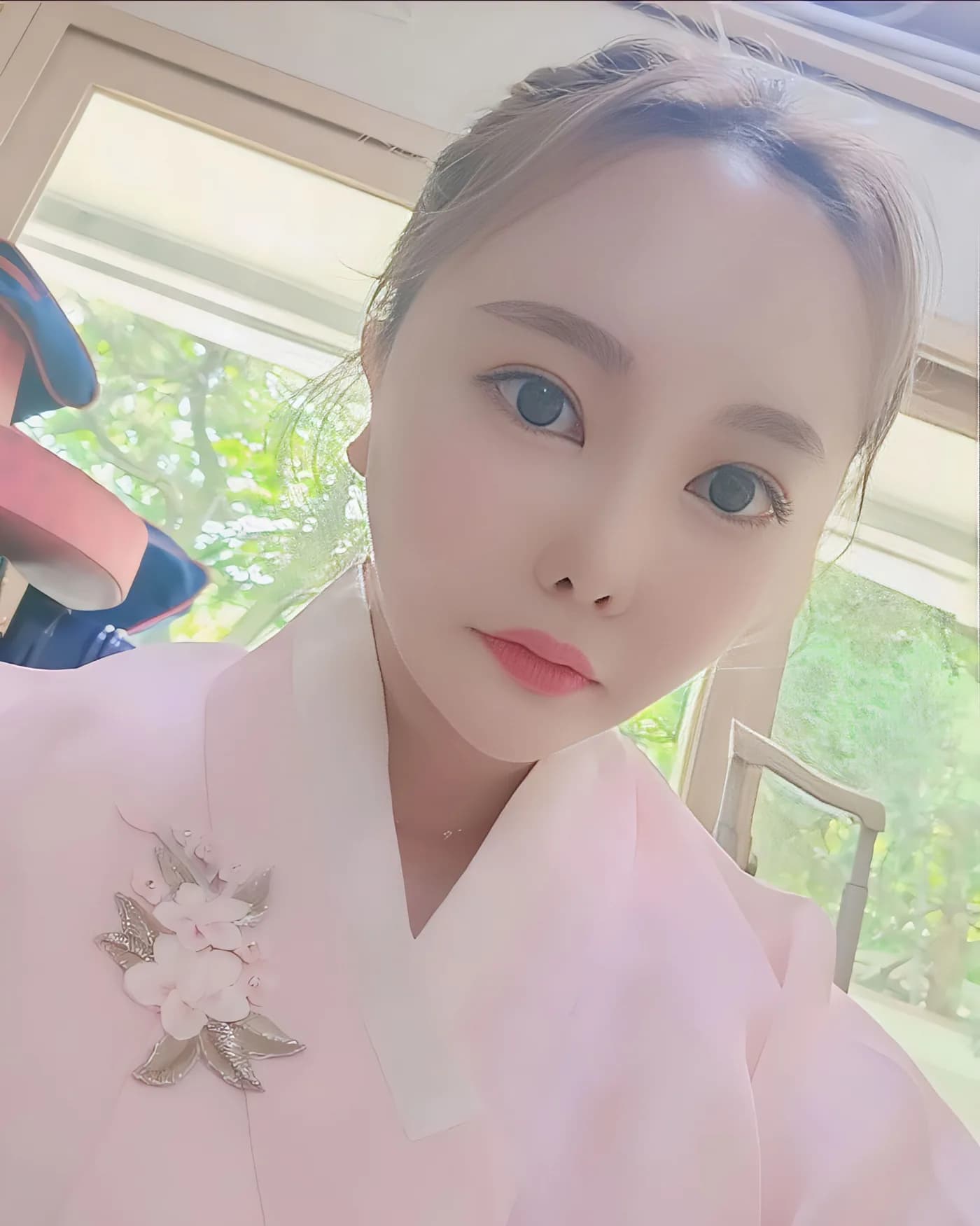 창가에서 꽃 장식을 단 분홍 한복 차림